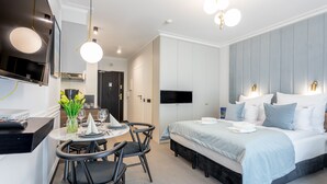 Ett modernt hotellrum med en säng, sängbord, ett skrivbord med stolar och en TV.