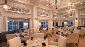 A spacious dining area with multiple tables and chairs, large windows, and elegant chandeliers. - Orion's Retreat a charming cottage nestled by the scenic shores of Lake Sinclair (Eatonton)