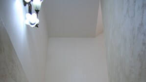Un escalier avec une rampe, un luminaire au-dessus et une grille d’aération sur le mur.