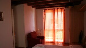 Une chambre à coucher avec un lit, une chaise et une fenêtre avec des rideaux.