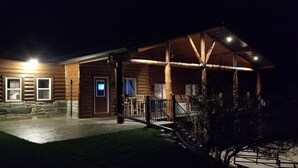 A log cabin with a covered porch, stone steps, and a well-lit entrance. - A Cabin in Rochford (Hill City)