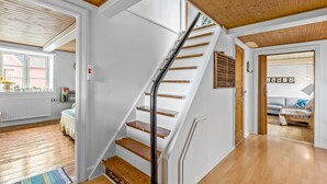 Eine Treppe mit Holzboden und Metallgeländer, die zu einem Raum mit Holzbalkendecke und Fenster führt.