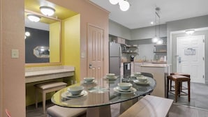 A modern kitchen with a glass dining table, a refrigerator, and a sink. - Designer 3BR/2BA Corner Suite - Disney & Universal (Orlando)