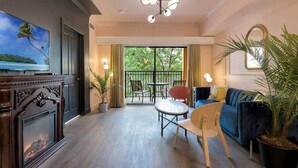 A modern living room with a fireplace, a sofa, a dining table, and a balcony with outdoor seating. - Designer 3BR/2BA Corner Suite - Disney & Universal (Orlando)
