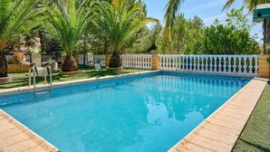 A rectangular swimming pool with a tiled edge, surrounded by a white fence, palm trees, and a stone fountain. - Pet friendly home in Doña Mencía (Doña Mencía)