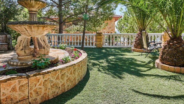 A garden with a stone fountain, palm trees, and a white fence. - Pet friendly home in Doña Mencía (Doña Mencía)