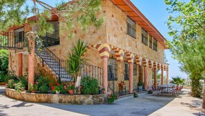 A two-story building with stone walls and a tiled roof, featuring a staircase, outdoor seating area, and potted plants. - Pet friendly home in Doña Mencía (Doña Mencía)