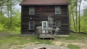 A two-story wooden house with a central door and two windows on each floor. - Cozy cabin in the woods (Evart)