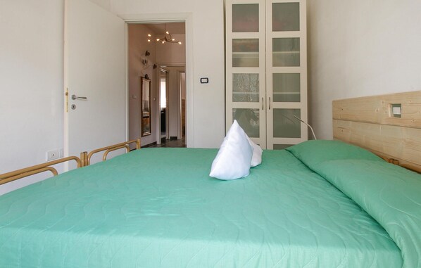 Un dormitorio con cama, cabecera de madera, espejo y armario con puertas de cristal esmerilado.