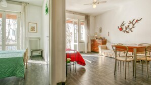 A spacious room with a bed, a dining table with chairs, a red umbrella, and a radiator.