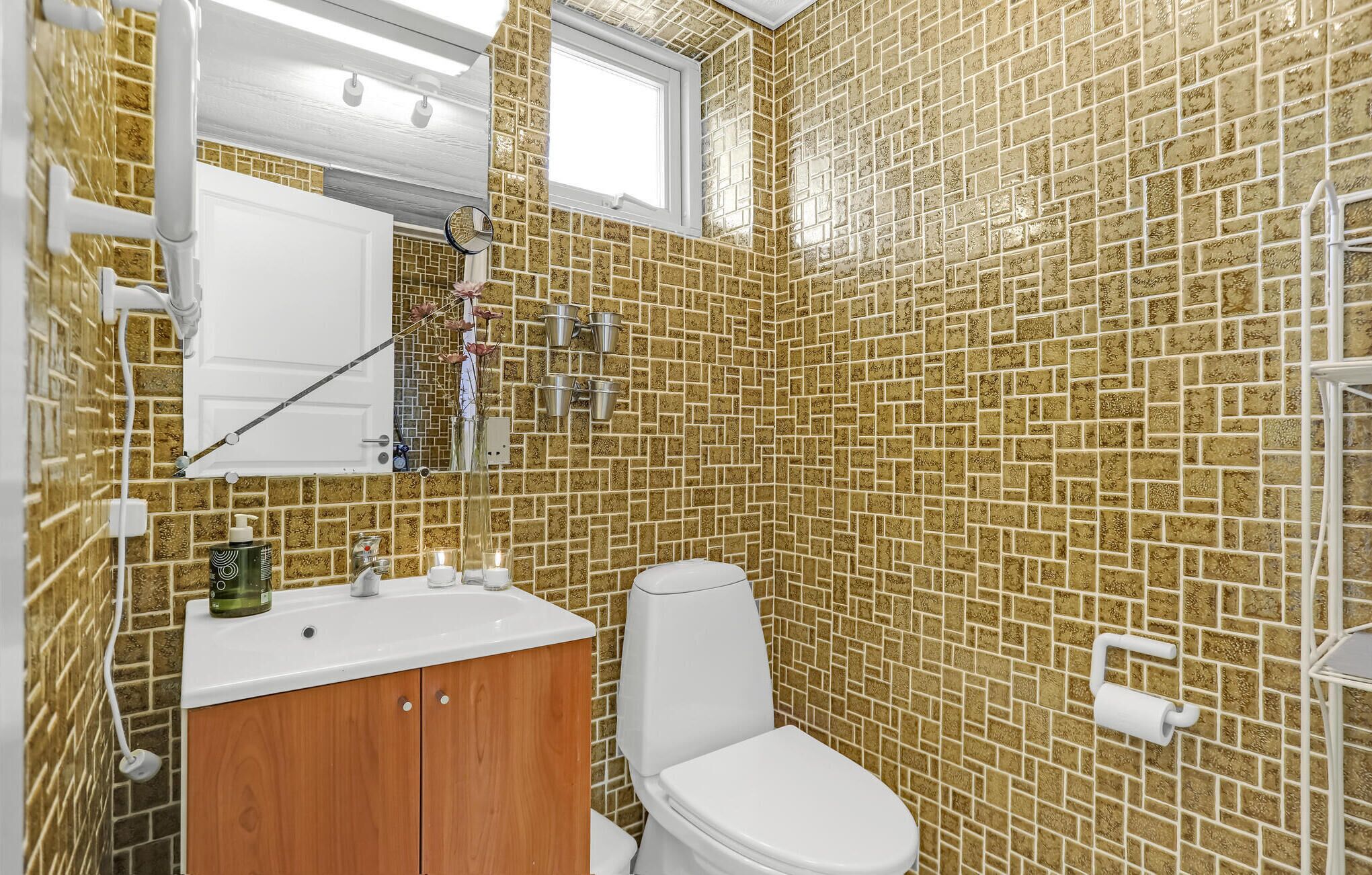 Ein Badezimmer mit Toilette, einem Holzkabinent und einem Waschbecken mit Spiegel darüber.