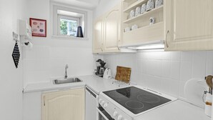 Una cocina moderna con armarios blancos, estufa empotrada, un lavabo y una ventana sobre el lavabo.
