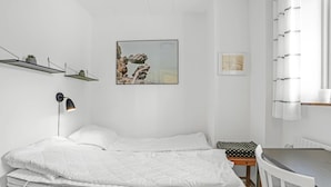 Un dormitorio minimalista con cama, mesita de noche y un pequeño escritorio.