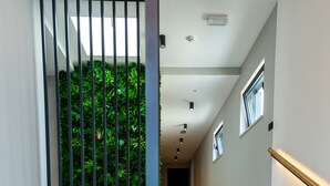 Una escalera moderna con barandilla de vidrio, un espejo redondo y una consola decorada con objetos ornamentales.