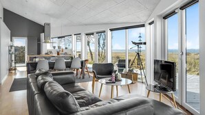 Una sala de estar moderna con un sofá grande, un comedor y un televisor.