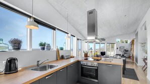 Una cocina moderna con una isla central, horno empotrado y un amplio ventanal con vistas panorámicas.