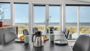 Un comedor con una mesa lista para dos personas, una tetera y vista al mar.