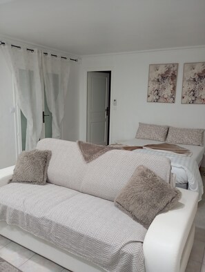 Une chambre à coucher avec un canapé, un lit et deux tableaux représentant des fleurs, accrochés au mur.