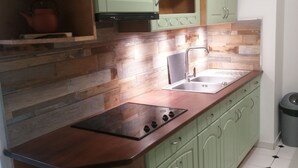 Une cuisine avec des meubles de couleur verte, un plan de travail en bois et un revêtement mural en carreaux.
