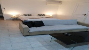 A bedroom with a bed, a sofa, a coffee table, and two bedside lamps. - 10 min. from Cannes, garden level with private pool, ideal for families (Le Cannet)