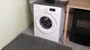 Un espace réduit dédié à la buanderie, comprenant un lave-linge, un étendoir et une petite table.