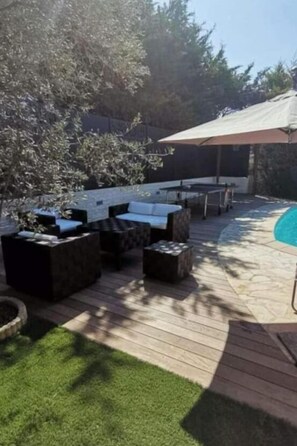 Un espace extérieur aménagé avec une terrasse, une piscine, une plateforme en bois et des coins salon.