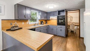 A modern kitchen with grey cabinets, a wooden countertop, and a built-in oven.