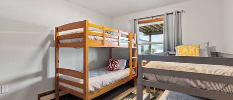 Habitación con literas, una ventana, una lámpara en el techo y un cajón pequeño debajo de la cama.
