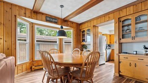 Una cocina con paneles de madera, una mesa de comedor y sillas, un refrigerador y armarios.