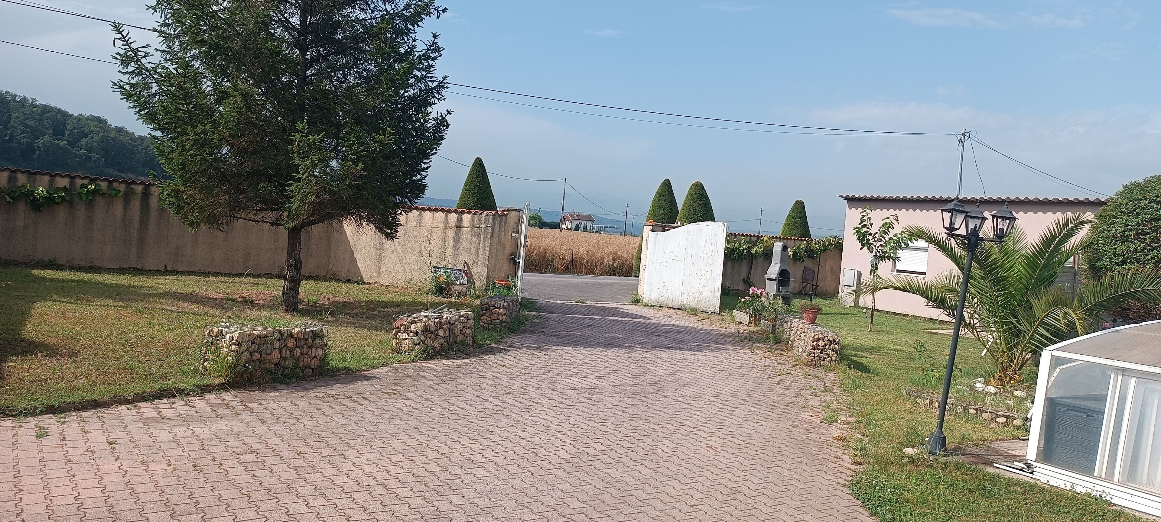 A paved pathway leading to a building with a tiled roof and a stone wall.