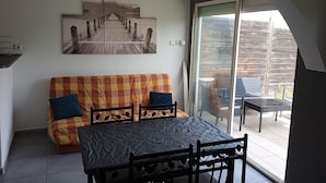 Une pièce confortable avec un canapé, une table et une porte vitrée donnant sur un espace extérieur.