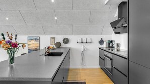 A modern kitchen with a large island, a built-in oven, and a stainless steel range hood.