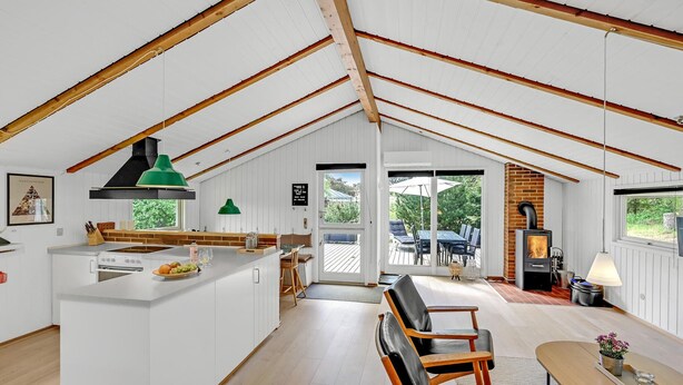 Ein geräumiges Loft mit hohen Decken, einer Küche mit Kochinsel, einem Essbereich mit Tisch und Stühlen sowie einem Kamin.