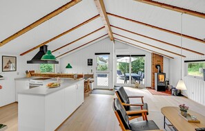 A spacious loft with high ceilings, a kitchen with a central island, a dining area with a table and chairs, and a fireplace.