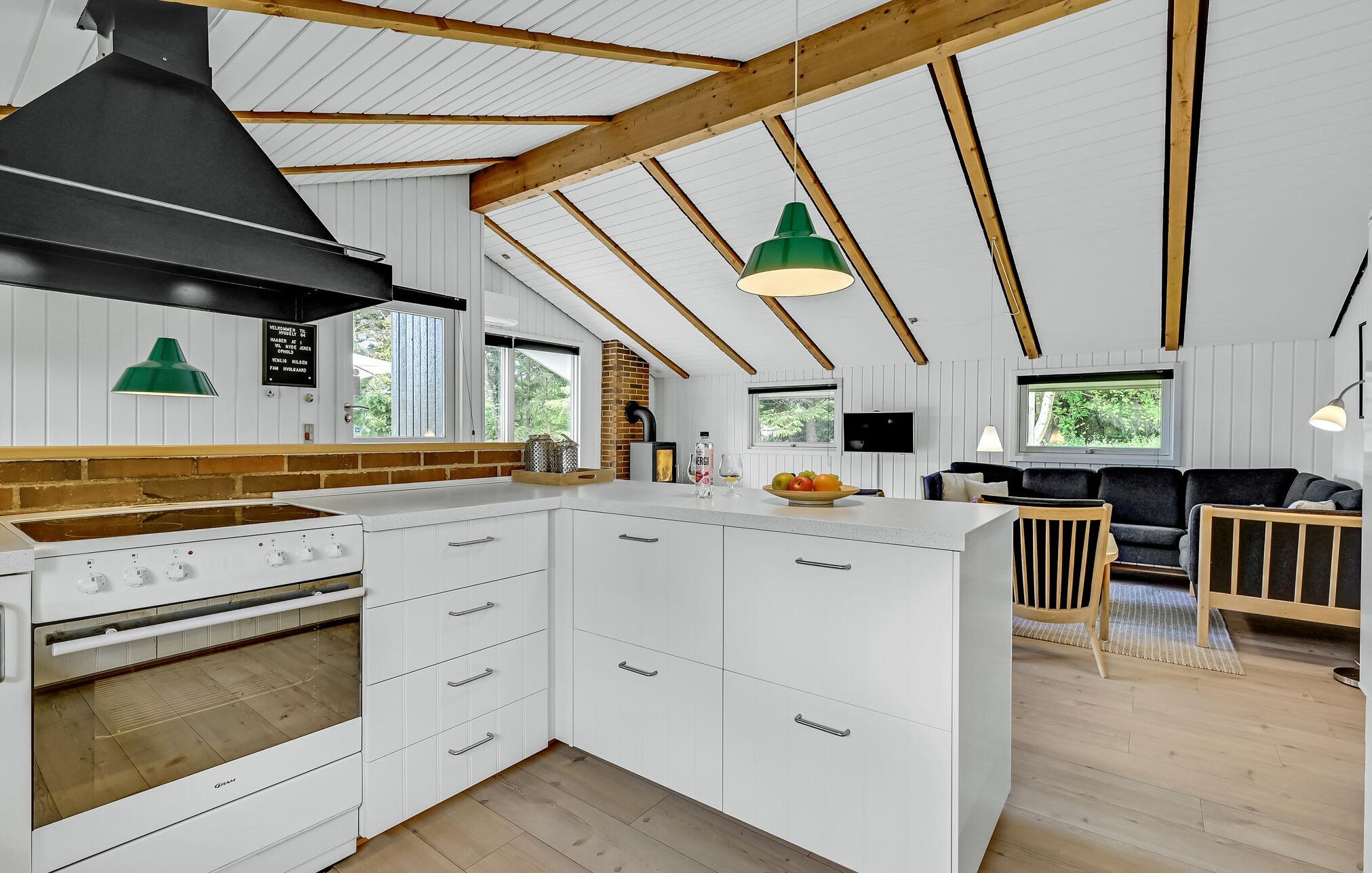 Een moderne keuken met witte kastjes, een groot eiland en een zwarte afzuigkap.