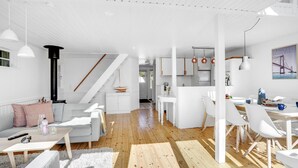 Een moderne, goed verlichte woonkamer met een bank, salontafel en een eethoek met stoelen en een tafel.