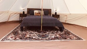 A tent with a bed, pillows, a rug, and two nightstands with lamps. - Sequoia Dawn  (Three Rivers)