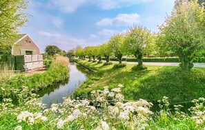 A canal with a row of trees and a building on the left. - Awesome home in De Heen with WiFi (De Heen)