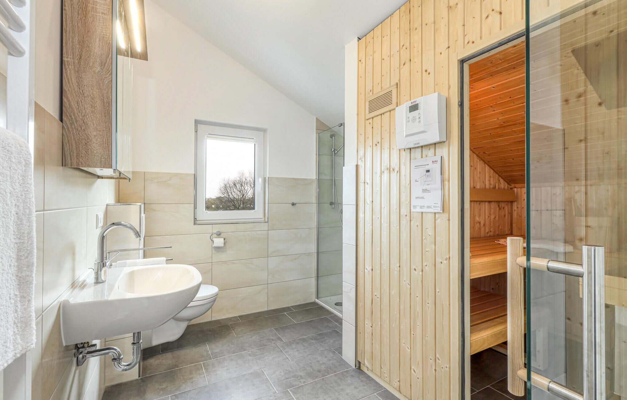 A modern bathroom with a sink, toilet, and shower.
