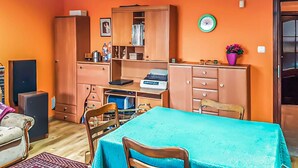 A room with orange walls, a wooden cabinet with drawers, a table with a blue tablecloth, and a clock on the wall. - Gorgeous home in Raciaz with WiFi (Raciaz)