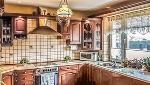 A kitchen with wooden cabinets, a stove, a microwave, and a window with a view. - Gorgeous home in Raciaz with WiFi (Raciaz)