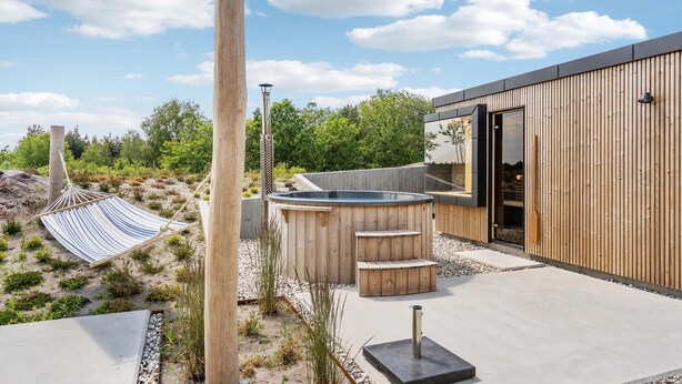 Un espace de détente extérieur moderne, doté d’un jacuzzi, d’un hamac et d’une terrasse en bois.