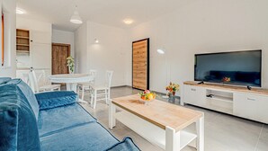 Una sala moderna con un sofá, una mesa de comedor con sillas, un televisor y un mueble de madera.