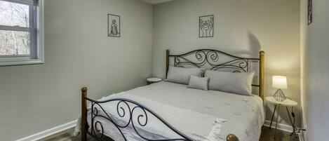 A bedroom with a metal bed frame, a bedside table with a lamp, and two wall-mounted pictures.