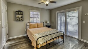 A bedroom with a bed, a ceiling fan, a window, and a door. - Lake, Fun, BBQ & Family. Charming & Cozy HOME! (morganton)
