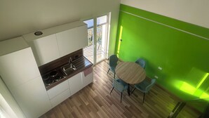 Eine moderne Küche mit Gasherd, weißen Schränken und einem Essbereich mit zwei blauen Stühlen und einem runden Tisch.