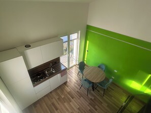 Eine moderne Küche mit Gasherd, weißen Schränken und einem Essbereich mit zwei blauen Stühlen und einem runden Tisch.
