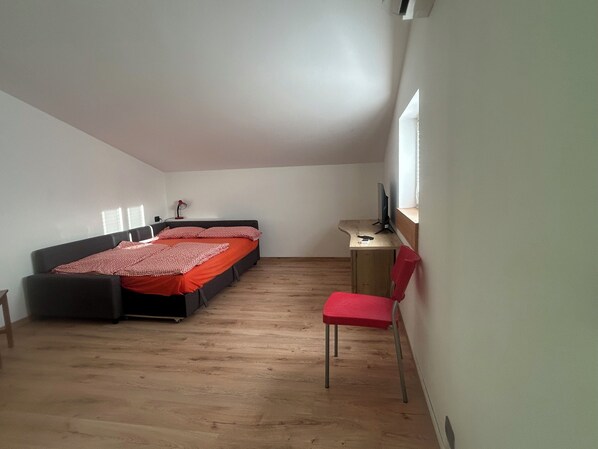 Een slaapkamer met een bed, een bureau, een stoel en een raam.