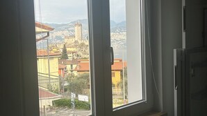 Ein Zimmer mit Fenster und Blick auf eine Stadtlandschaft, darunter ein Turm und Gebäude.