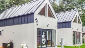 Un edificio moderno con techo inclinado, ventanas amplias y una escultura en el interior.